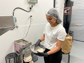 Woman smiling holding a metal bowl of flour.