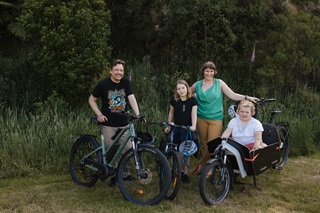 Family standing and smiling for a photo with their bikes.
