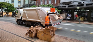 Street cleaners at work putting recycling in a truck.