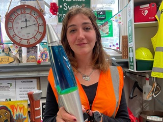 Woman holding up a blue lava lamp.