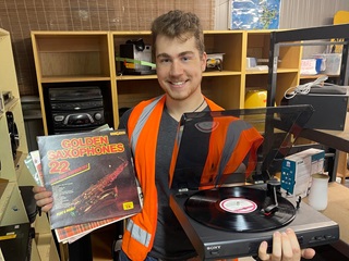 Person holding up a record and a record player.