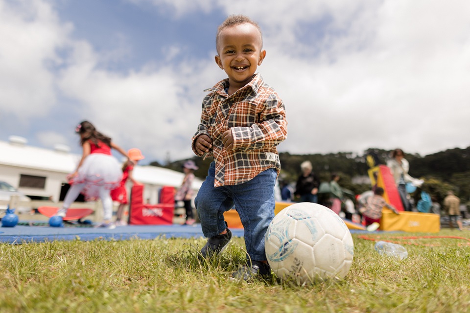 Young boy in park playing with a football