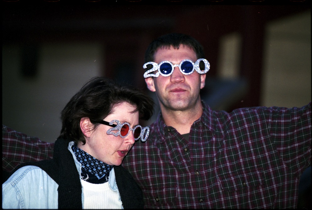 Couple of people with 2000 shaped glasses on celebrating at New Year's Eve event 31 December 1999