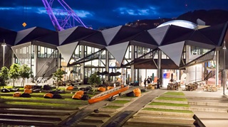 The Wharewaka on the Wellington waterfront at dusk with lights on side the building.