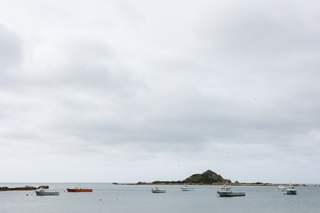 Island Bay Taputeranga island surrounded by boats in the water.