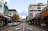 An empty street with no people around and a couple of cars pared on one side. 