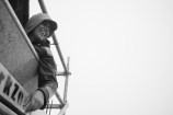 Person sitting with an arm hanging out the side of a waka with their hood up.