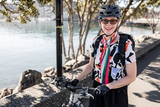 Woman smiling by her bike on the waterfront.