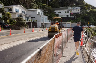 Man running on a footpath on the right hand side of the road.