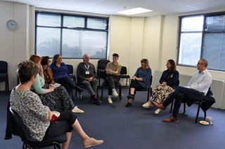 Group of people sitting in a semi-circle having a conversation.