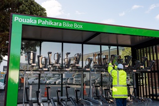 Person wearing a yellow high vis jacket doing work on a bike shelter.