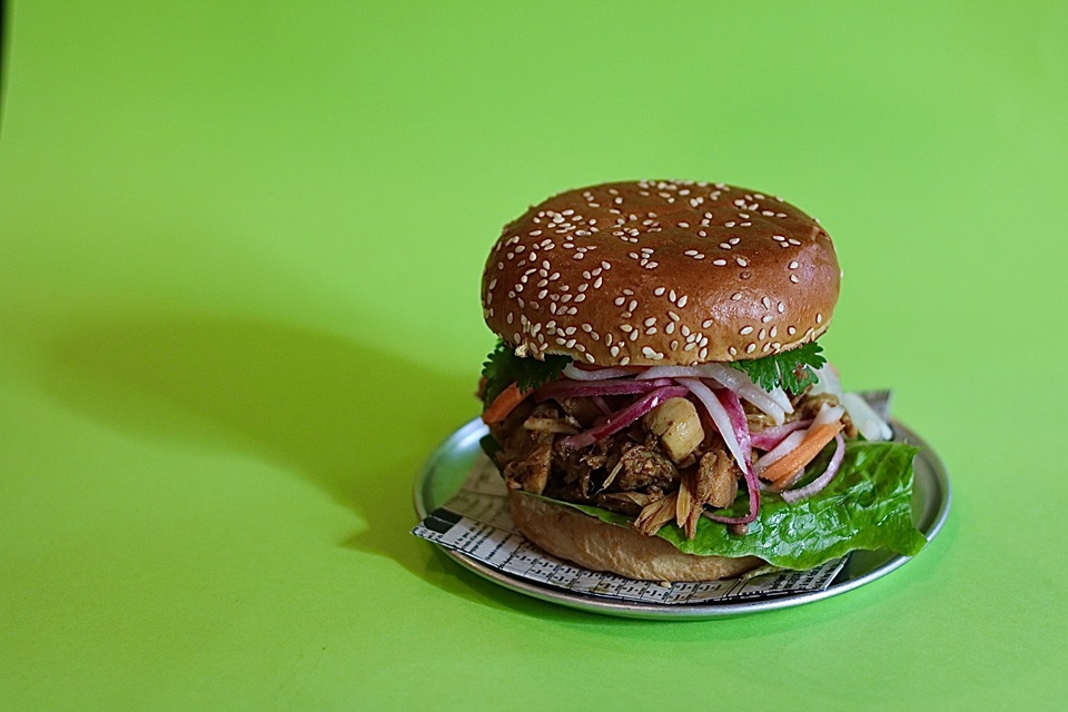 Halkatraz burger by Chaat Street on table with green background.