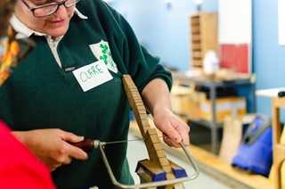 Person demonstrating woodworks to another person.