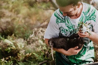 Kiwi being held by a worker.