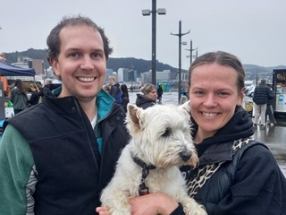 Two people holding up a white dog.