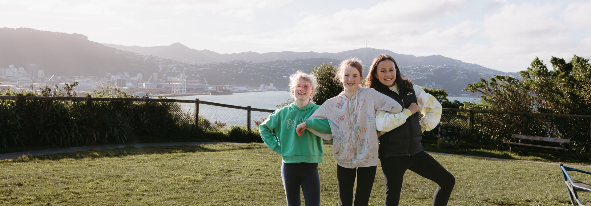 Three girls standing on equipment at a playground.