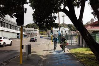 Two people riding a bike over blue markings on the ground.