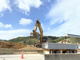 Yellow digger picking up rocks at the work site.