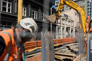 Worker at a construction site with a yellow digger in the background.