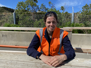 Woman in high vis sitting at a table.