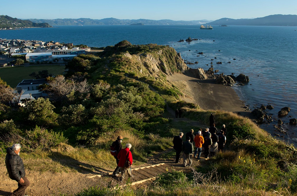 People walking along a pathway overlooking water.