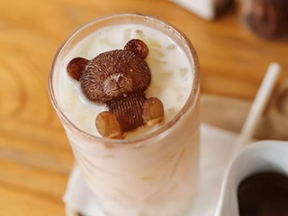 Iced coffee on a table with a bear ice cube on top.