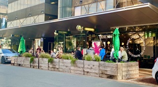 Parklet on the side of the road with people eating outside.