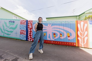 Person standing infront of a mural with colourful images.