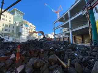 image of debris from the CAB demolition being raked by a digger in the background