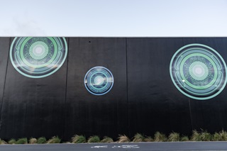 Blue and green auripo rippling out across a black wall.