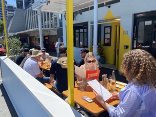 Two people sitting outdoors in a parklet, ordering things from the menu.