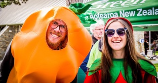 Two people side by side, with the one on the left dressed as a carrot and the one on the right dressed as a strawberry.