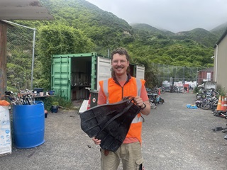 A man in high vis holding flippers in his hands.