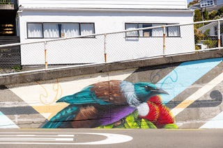 A painted tui as part of a mural on the side of a concrete wall.