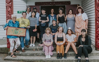 Group of people sitting on steps with a sign that reads 'Seeds to feeds'.