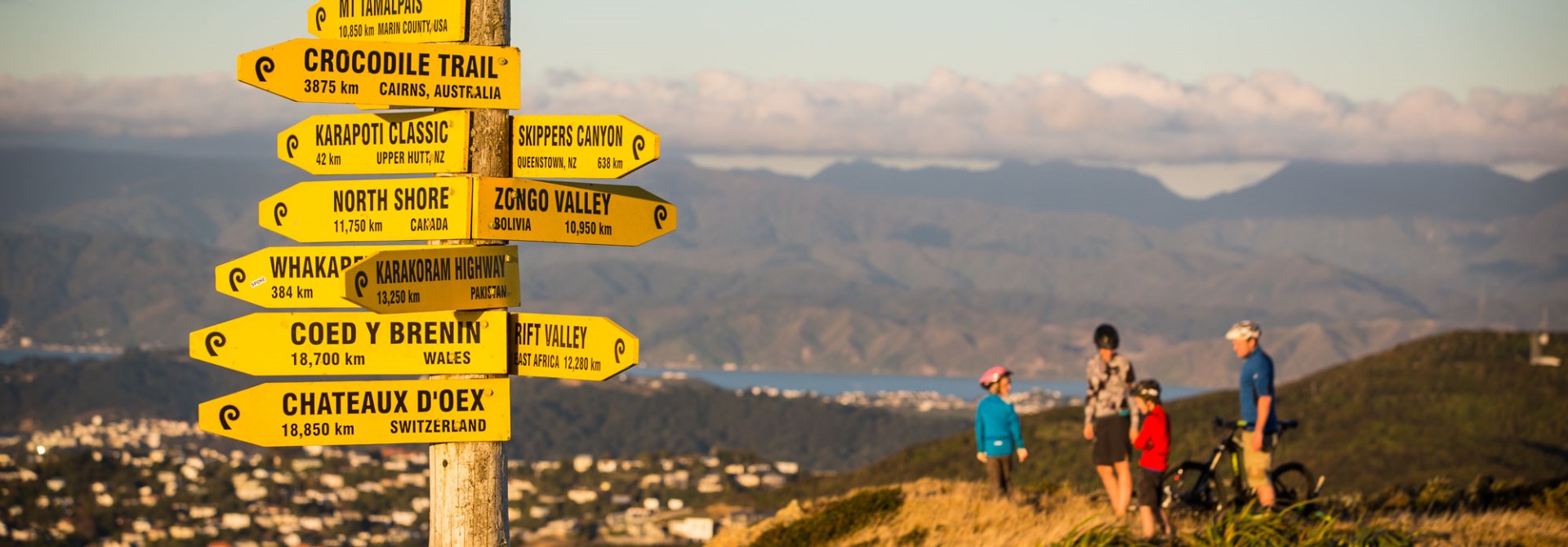 Signs on top of Makara Peak with people on bikes behind it.