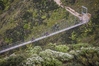People crossing a bridge on bikes.