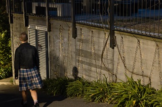 Person walking down a pathway at night with fairy lights strung up on the wall. 