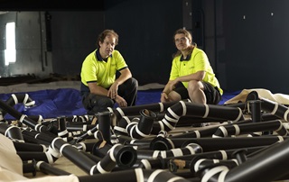 A man and a woman standing over zinc trunks of an organ.