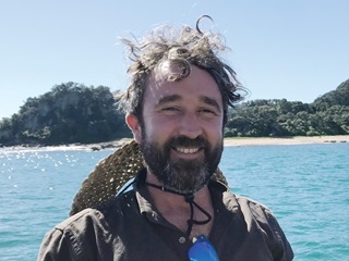 Man smiling infront of the water.