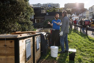 Two people having a discussion next to a planter box.