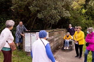 Groups of people standing around a planter box as somebody does a talk.