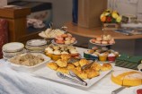 A table laden with a while table cloth and an elaborate morning tea spread.