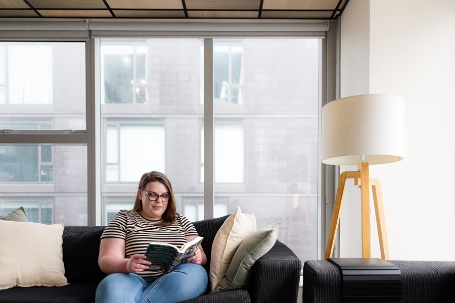 Woman sitting on a couch reading a book.