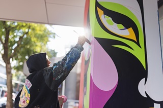 Xoë Hall  painting the Te Tai Ohinga Mural