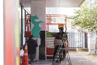 Xoë Hall and youth painting the Te Tai Ohinga Mural