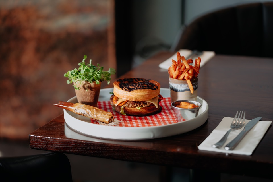 Winning burger from One80 with accompaniments set out on table.