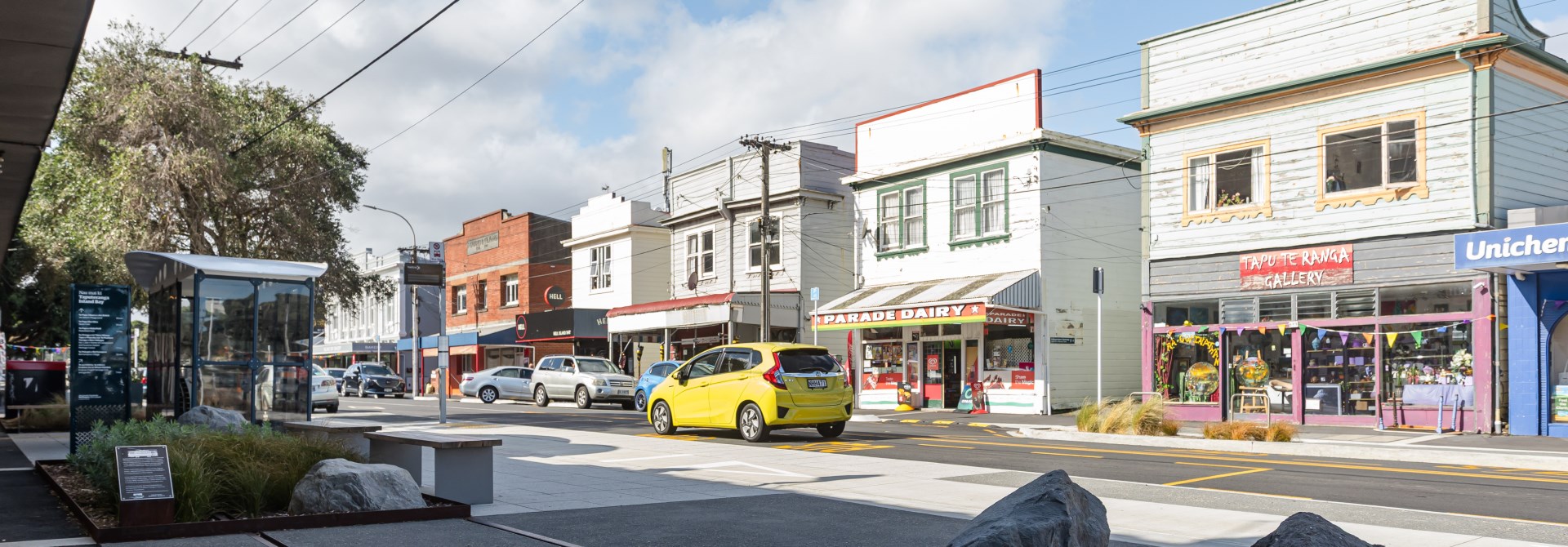 Urban streetscape with a close up of tram lines in the ground and shops in the background.