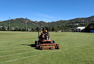 Man wearing high vis on a mower on a field.