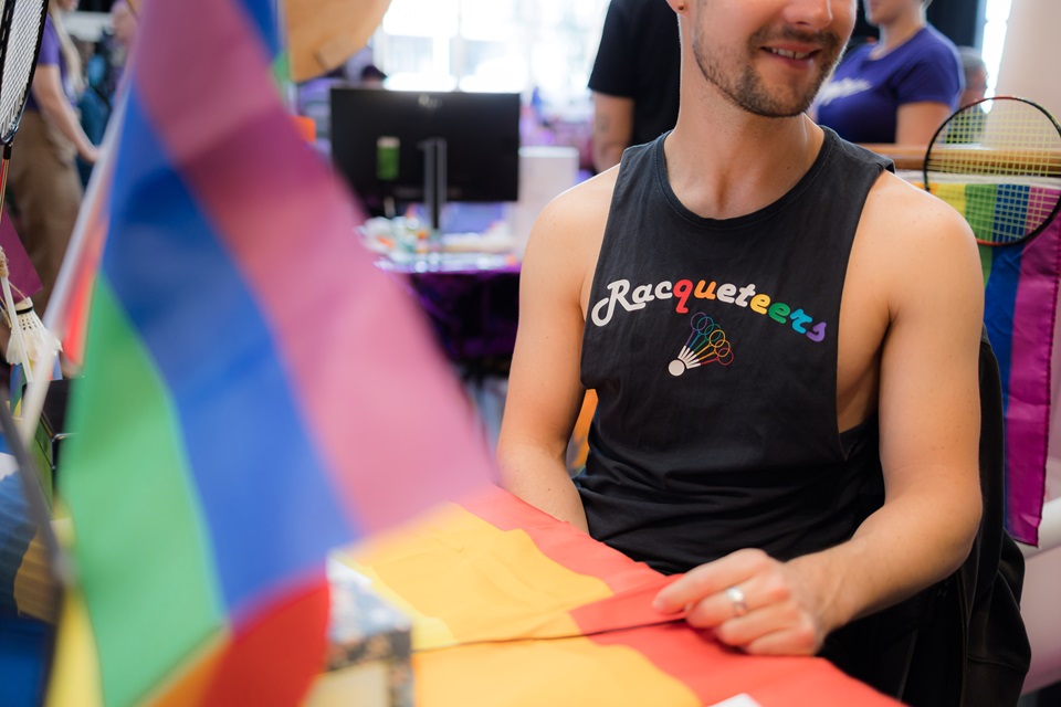 Pride Out in the City man wearing t-shirt for Racqueteers sports club.